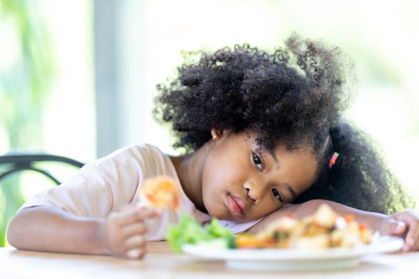 A young black girl shows signs of an eating disorder.