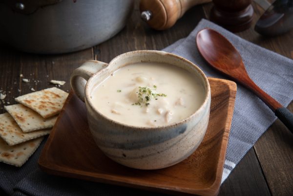 Clam chowder in a cup with cookies on the side