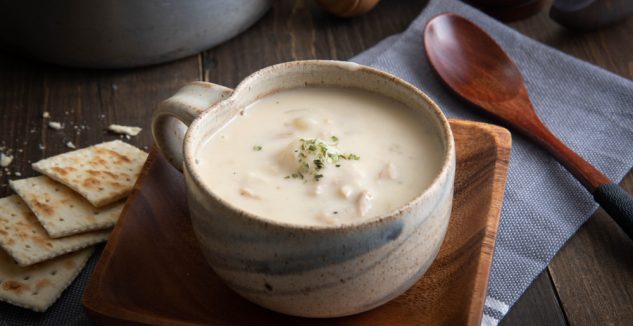 Clam chowder in a mug with crackers on the side
